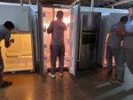 FAJ Technical Services technicians inspecting and servicing multiple commercial refrigerators in a warehouse setting in Dubai.