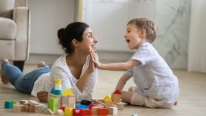 Happy nanny giving high five praise to excited preschool kid